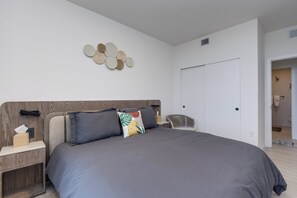 Un dormitori modern amb un llit gran, una tauleta de nit, una decoració circular penjada a la paret i un armari.