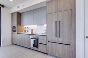 A modern kitchen with light wood cabinetry, stainless steel appliances, and a sleek countertop. - Luxury 4-bedroom condo At 72 Park With Gym, Pool, Tiki bar and Beach Service (Miami Beach)