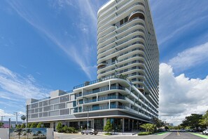 A modern multi-story hotel with a curved facade, large windows, and balconies.