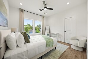 A modern bedroom with a bed, a desk, a chair, and a ceiling fan. - The Suite Spot: 4BR with 2 King Suites and Private Patio near NRG Stadium (Houston)