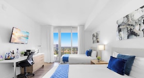 A modern hotel room with a large bed, a desk with a computer, a chair, and a view of the city through the window. - Elegant Modern Studio w/ Bay View & Resort Pool (Hallandale Beach)