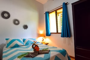 Ein Schlafzimmer mit Bett, Nachttisch, Lampe, einem Fenster mit Vorhängen und Wanddekoration.
