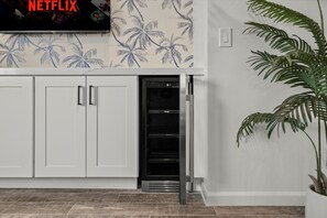 A kitchen with white cabinets, a built-in oven, and a wall-mounted television displaying 'NETFLIX'. - 2-bedroom condo with OCEAN VIEW, A/C, KING BED, STEPS AWAY FROM SAND (Oceanside)