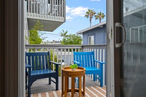A balcony with two blue chairs and a small table with a plant. - 2-bedroom condo with OCEAN VIEW, A/C, KING BED, STEPS AWAY FROM SAND (Oceanside)