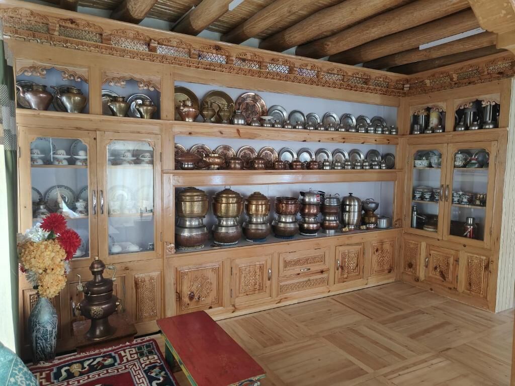 Una habitación con armarios de madera que exhiben diversos recipientes metálicos y cerámica.
