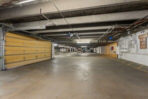Eine Tiefgarage mit Betonböden, gelben Garagentoren und sichtbaren Rohren an der Decke.