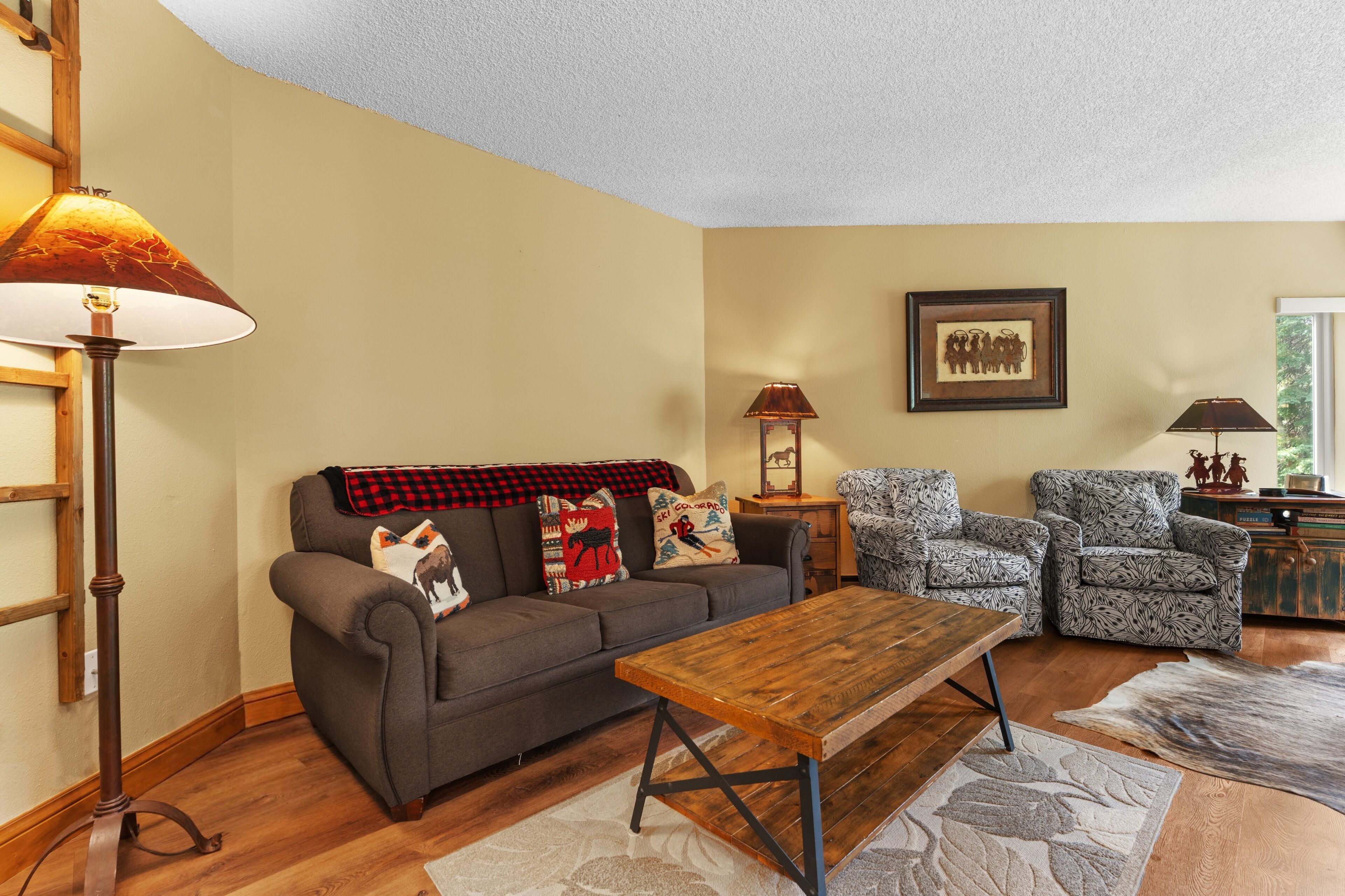 A living room with a sofa, two armchairs, a coffee table, a lamp, and a framed picture on the wall.