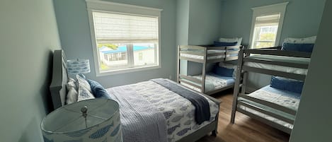 A bedroom with bunk beds, a window with blinds, a ceiling fan, and a lamp with a fish pattern.