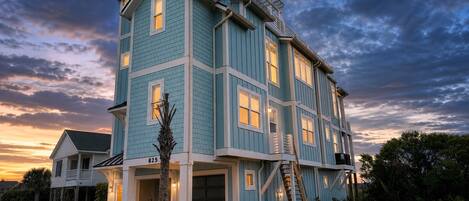 A multi-story house with a garage, a covered porch, and a staircase leading to the upper floors.