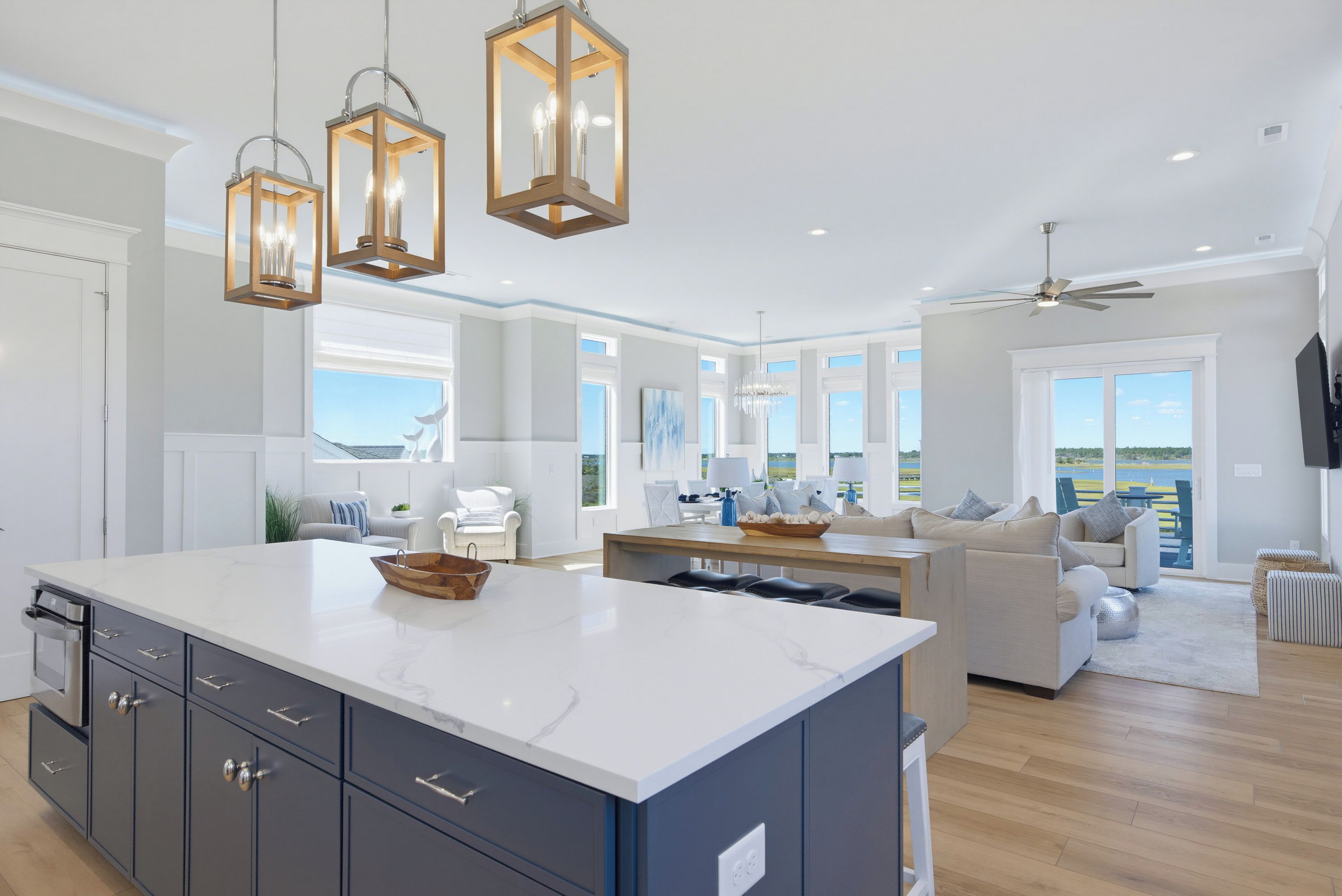A modern kitchen with a large island, pendant lighting, and a view of the outdoors.