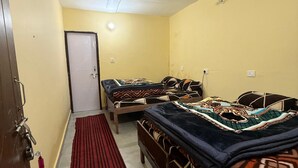 A room with two beds, a red rug, and a door.