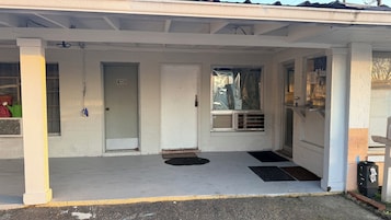 A covered porch with a door marked '100', a window with a view, and a small air conditioning unit.