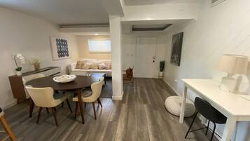 Ein modernes Interieur mit Essbereich, einer Couch und einer weißen Wand mit einem gerahmten Bild.