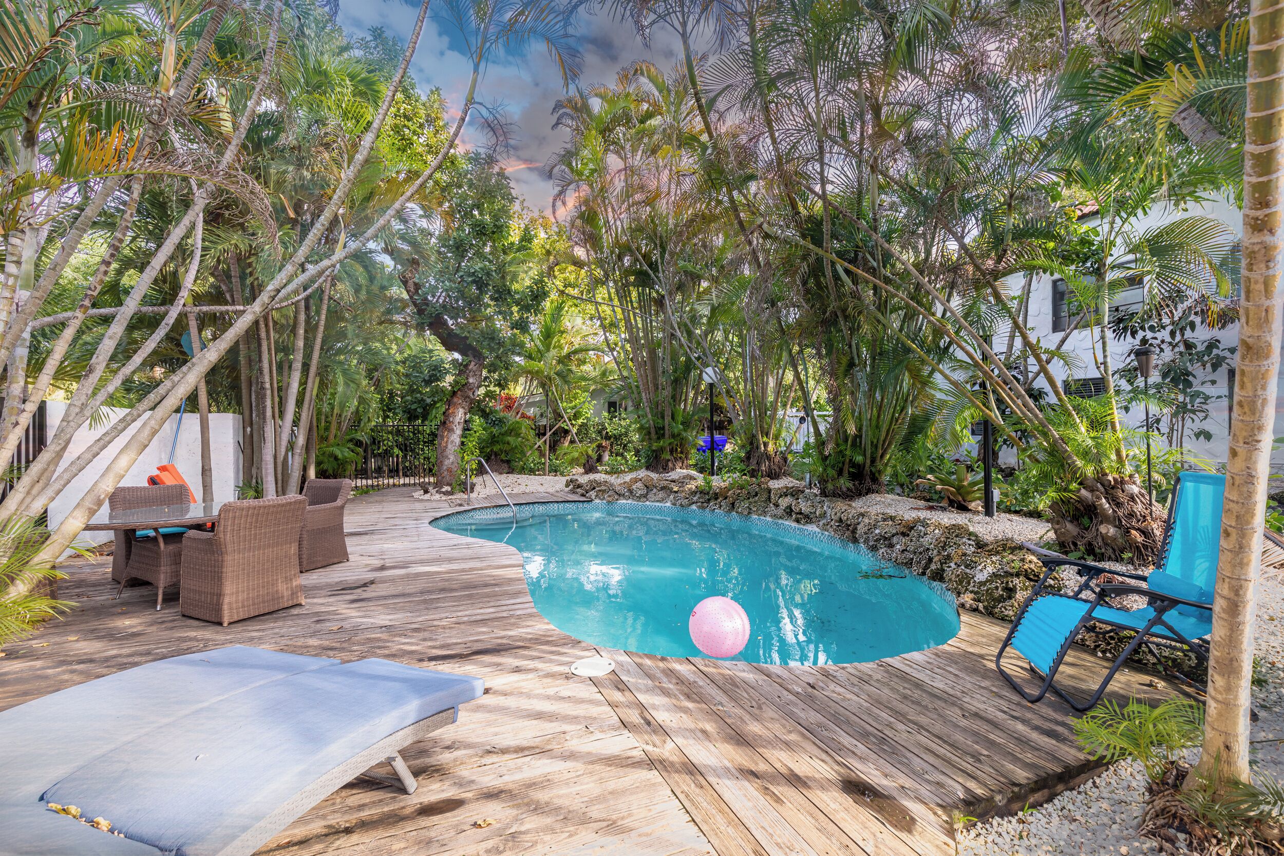 Eine Holzterrasse umgibt einen Swimmingpool mit Liegestühlen und einem Tisch.