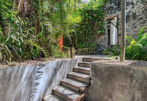 A concrete staircase leading to a stone building surrounded by dense tropical vegetation.