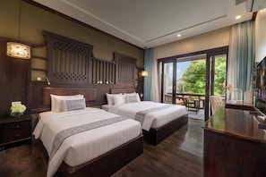 Habitación de hotel con dos camas, cabecera de madera, un escritorio y vistas al exterior.