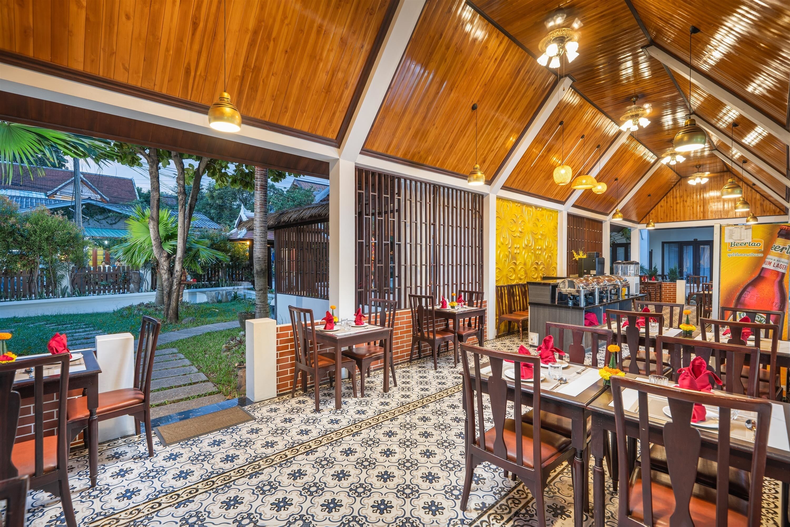 A restaurant with wooden ceiling beams, tiled flooring, and tables set for dining.