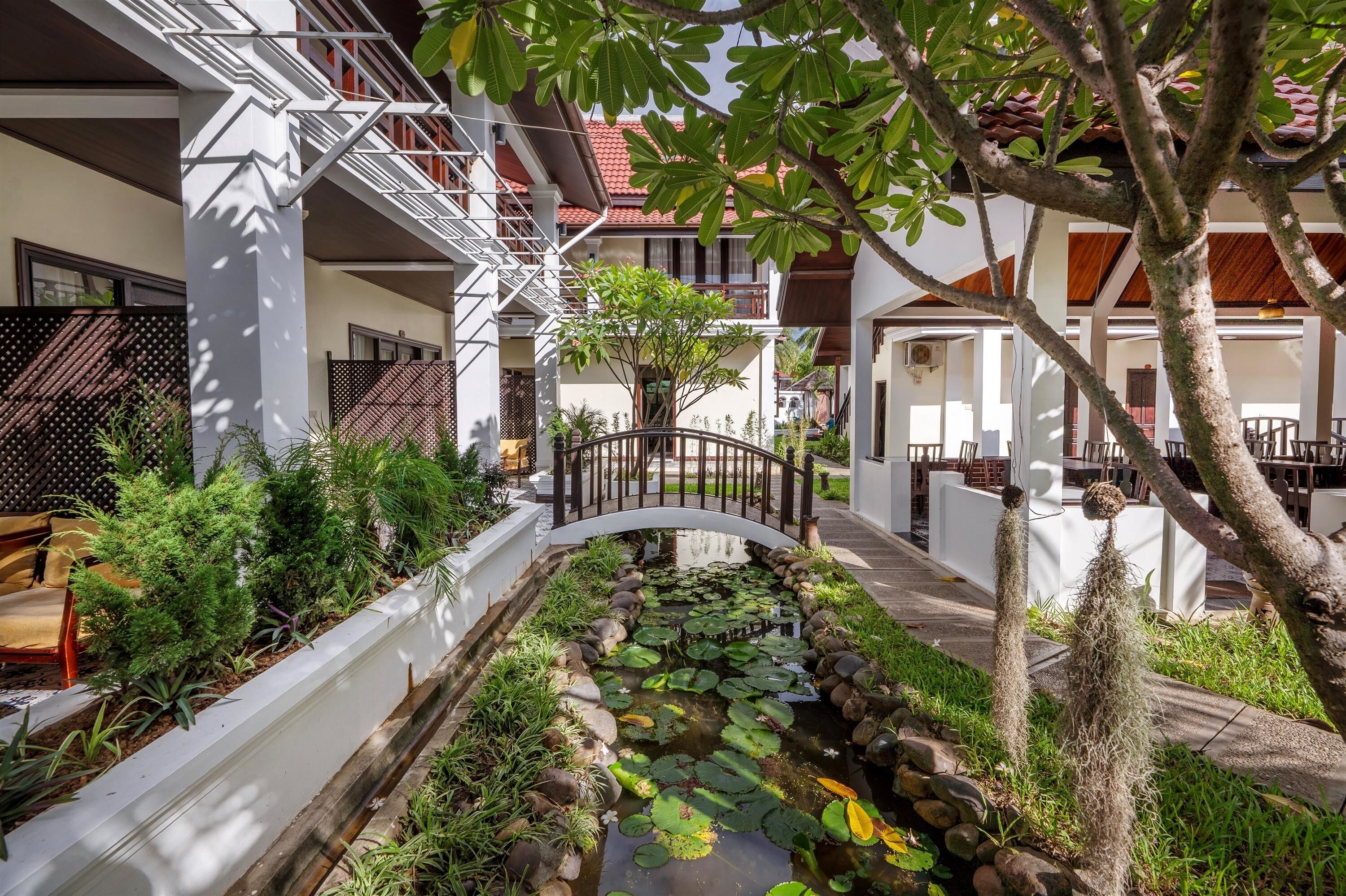 A courtyard with a water feature, a bridge, and a variety of plants.