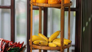 A wooden fruit stand with oranges and bananas, placed on a table with a window in the background.