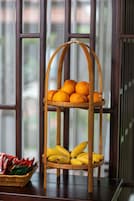 A wooden fruit stand with oranges and bananas, placed on a table with a window in the background.