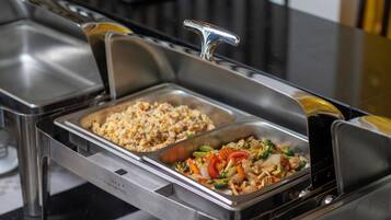 A buffet with two food dispensers, one with fried rice and the other with stir-fried vegetables.