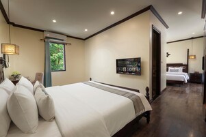 Una camera d'albergo con un letto grande, una TV a parete e una finestra con tende.