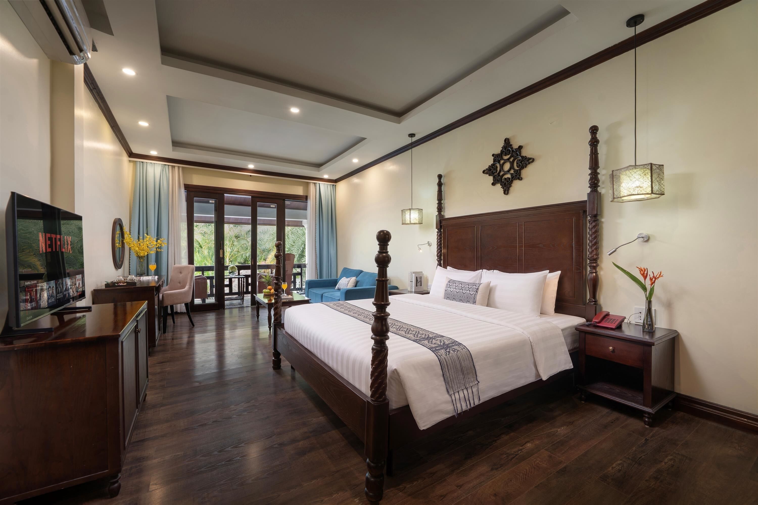 A hotel room with a large bed, a television, a desk, and a balcony with a view.