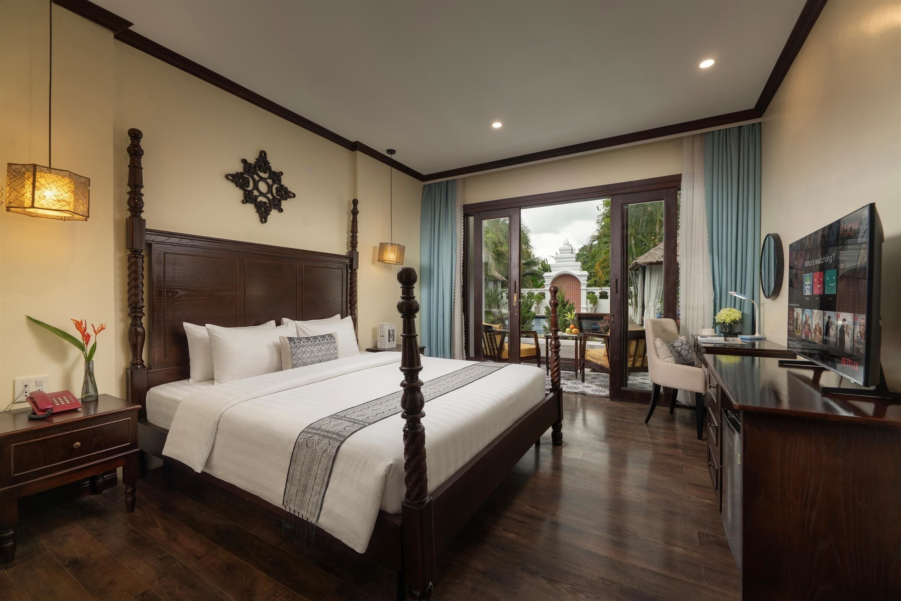A hotel room with a large bed, a desk, a TV, and a view of the outdoors.