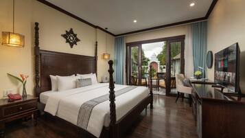 A hotel room with a large bed, a desk, a TV, and a view of the outdoors.