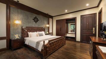 A spacious bedroom with a large bed, wooden wardrobe, and a desk with a chair.