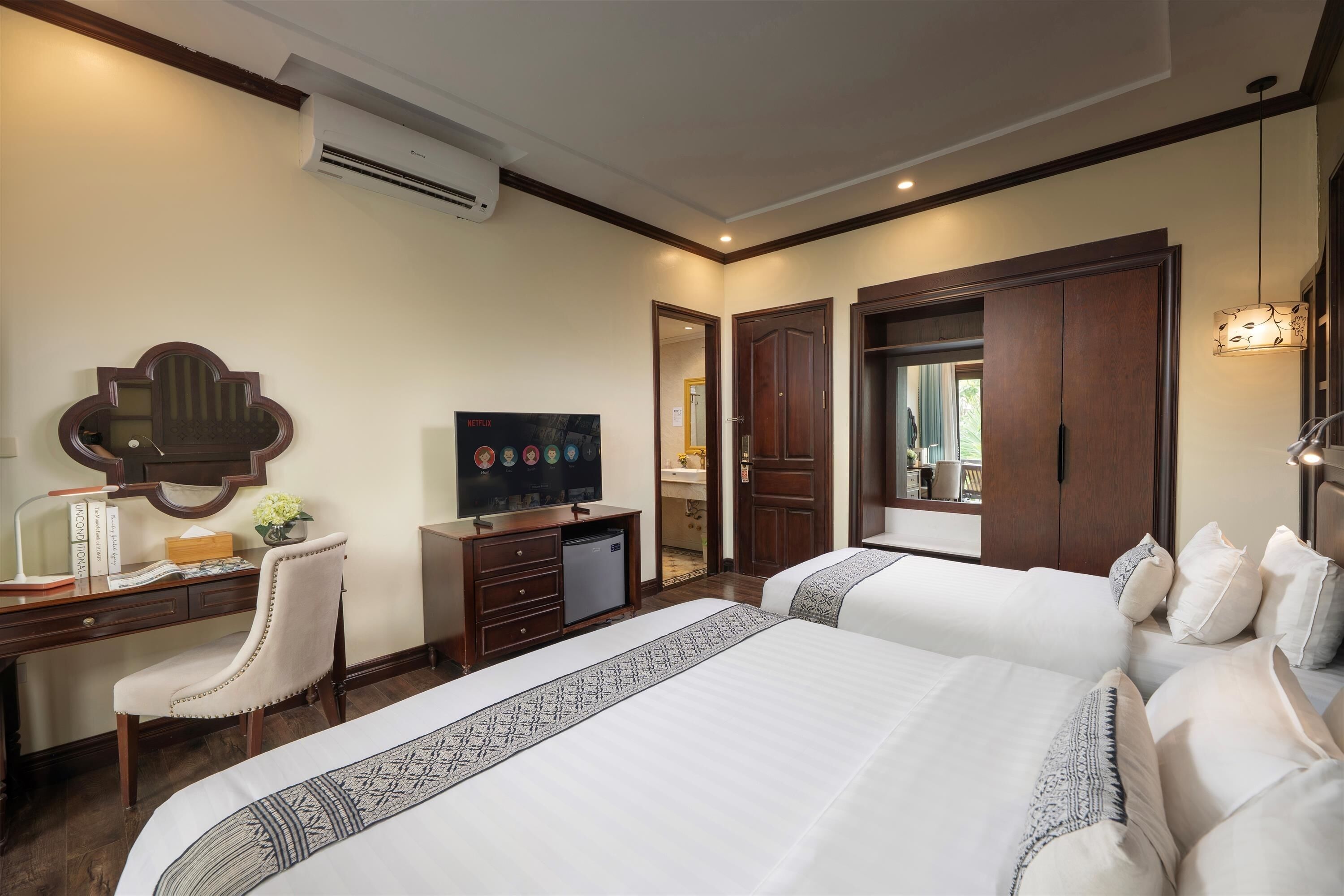 Une chambre d’hôtel comprenant un lit, un bureau avec un ordinateur, une télévision et une armoire.