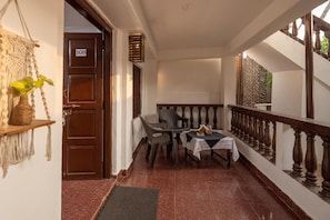 Un pasillo con una puerta de madera marcada '108', una pequeña mesa con mantel blanco y una silla.