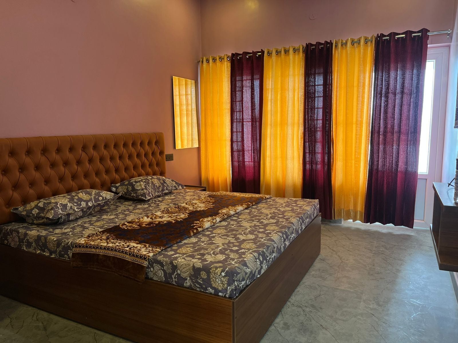 A bedroom with a large bed, a headboard, and curtains.
