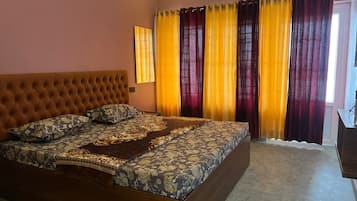 A bedroom with a large bed, a headboard, and curtains.