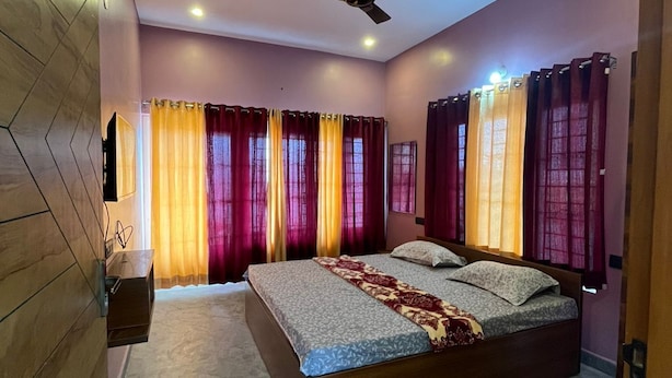 Un dormitorio con cama, cortinas, ventilador de techo y pared de madera.
