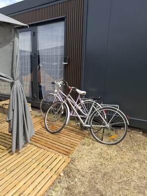 A bicycle parked outside a modern building with a wooden deck and a grey awning. - La Tiny de Touraine – Nature & Confort (Auzouer-en-Touraine)
