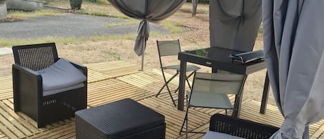 An outdoor patio area with a covered seating arrangement, including chairs and a table.