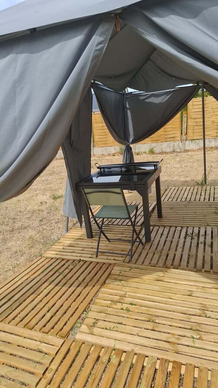 Une tente avec une table et des chaises installées sur une terrasse en bois.
