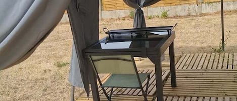 Une tente avec une table et des chaises installées sur une terrasse en bois.