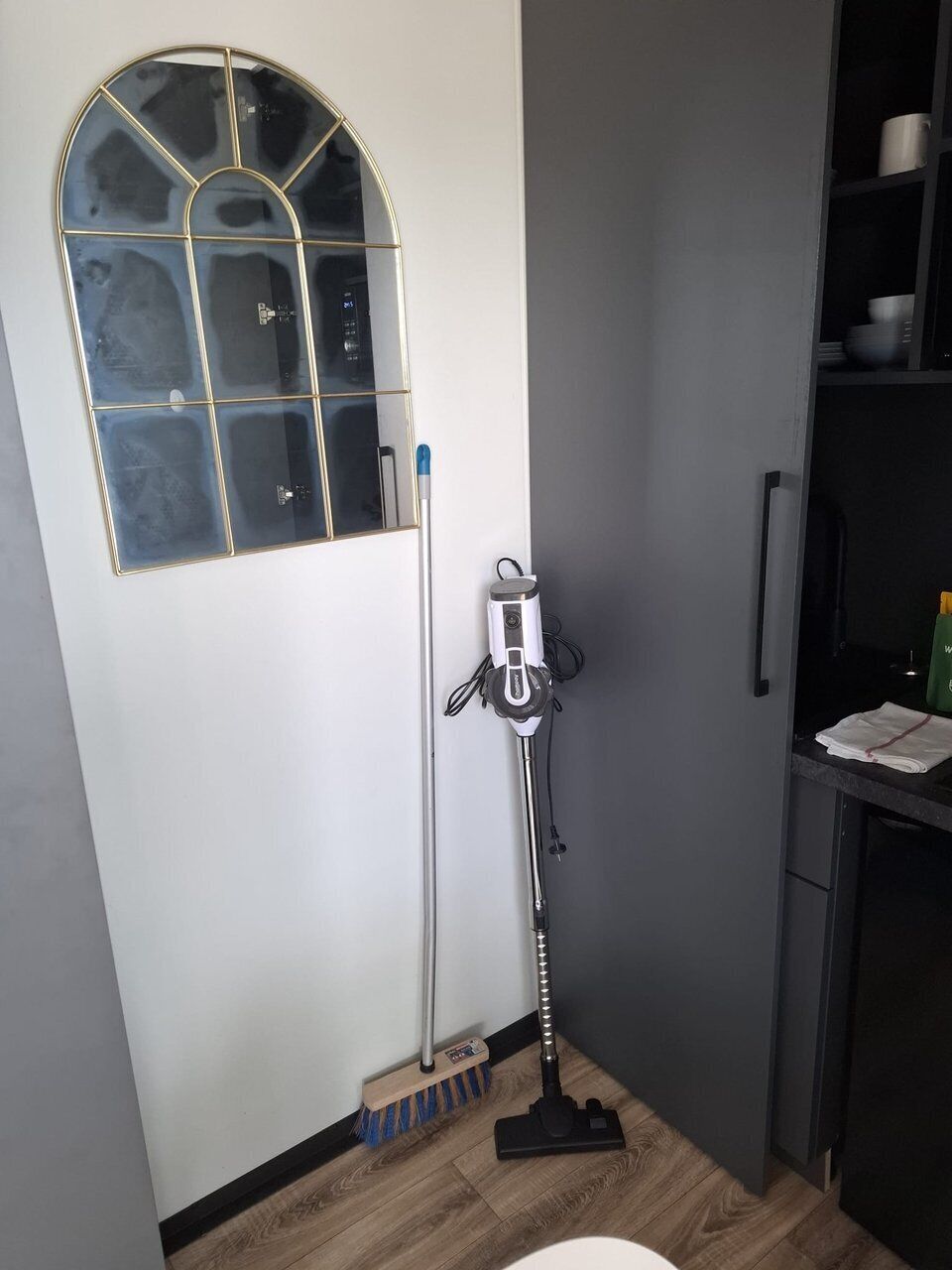 Une salle de bain avec un grand miroir, des toilettes, un lavabo et un aspirateur.