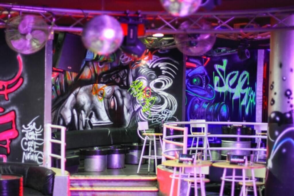 Een kamer met graffiti kunst, een grote bank en een bar met krukken.
