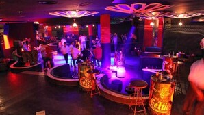A bar area with stools, a bar counter, and a crowd of people.