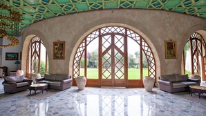 A spacious room with a high ceiling, large arched windows, and a marble floor.