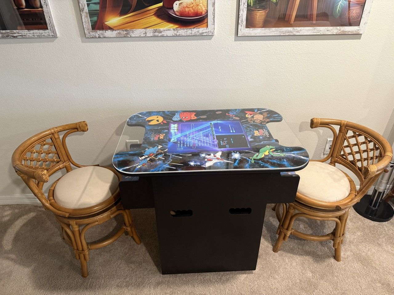 Una mesa con un diseño colorido en su superficie, flanqueada por dos sillas de mimbre con cojines.