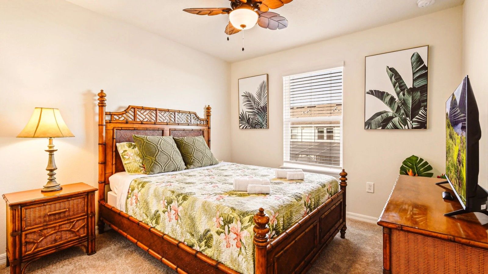 A bedroom with a wooden bed, a nightstand with a lamp, a window with blinds, and wall art.