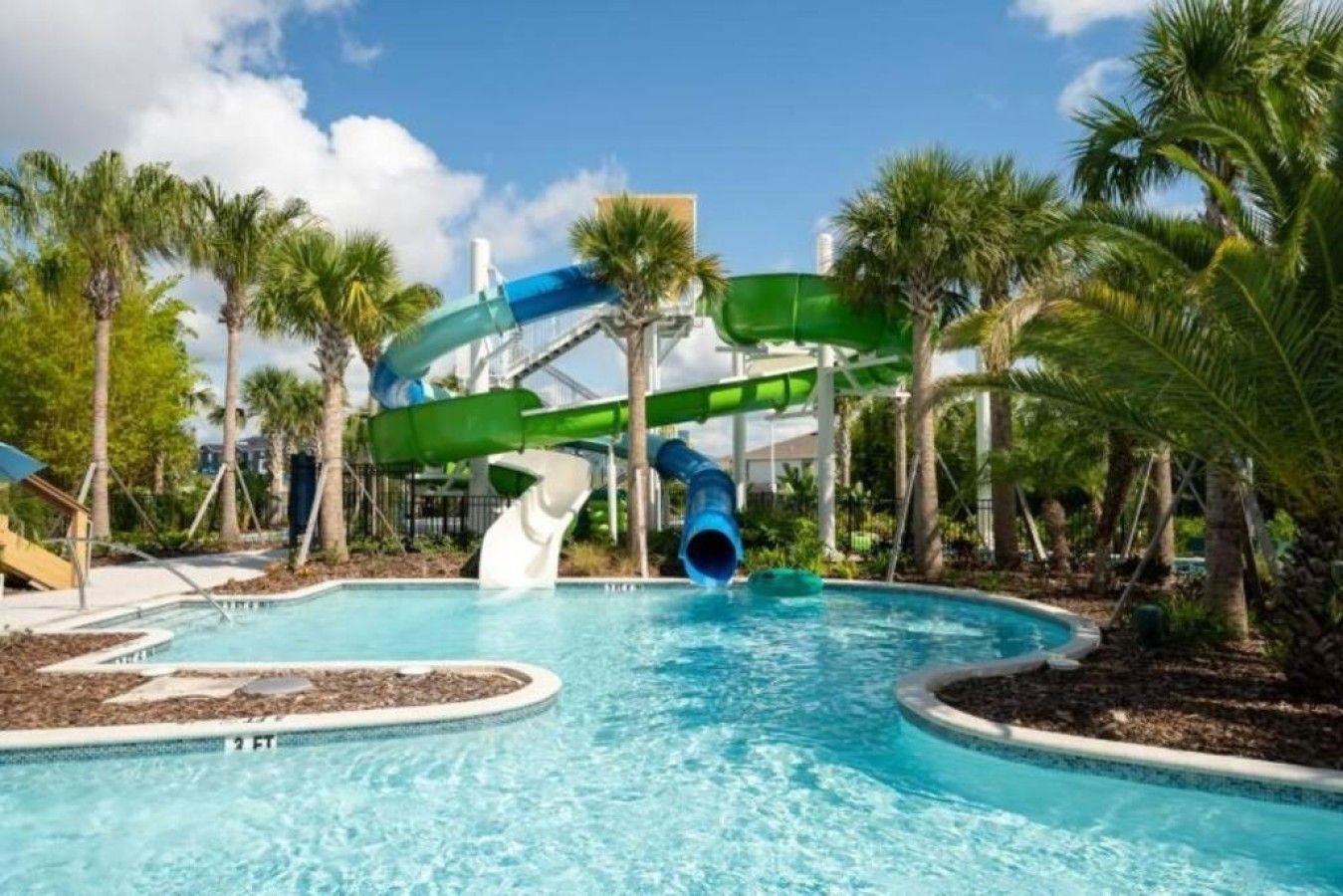 Un parc aquatique avec une piscine, des toboggans et des palmiers.
