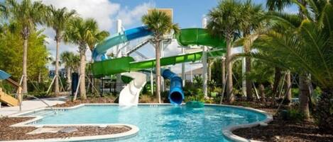 A water park with a pool, slides, and palm trees.