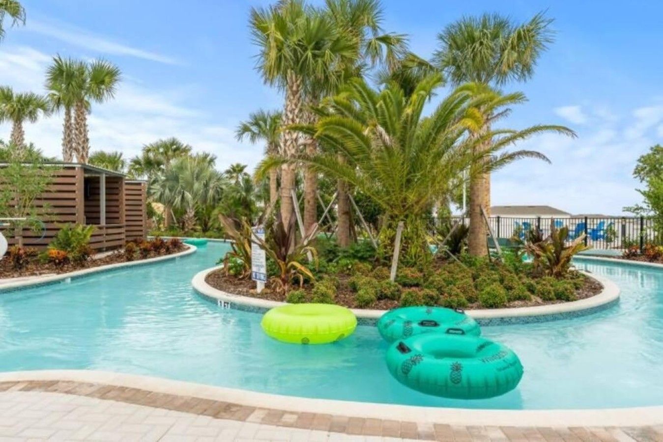 A swimming pool with palm trees and inflatable rings.