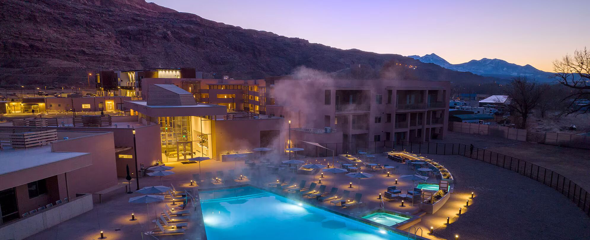 Un hôtel doté d’une piscine, de chaises longues et offrant une vue sur un paysage montagneux.