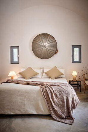 A bedroom with a bed, two bedside lamps, a wall-mounted circular light fixture, and two windows. - Trullo dei Noci, an historic trullo with a private pool (Ceglie Messapica)